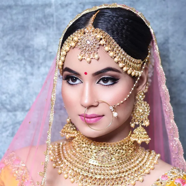 Bride in blue and gold with a pearl maang tikka