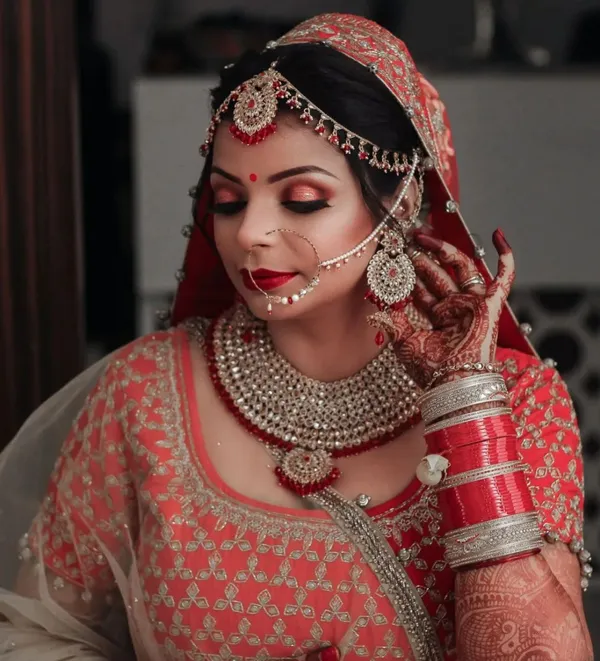 Bride in coral and peach wearing a gold nath