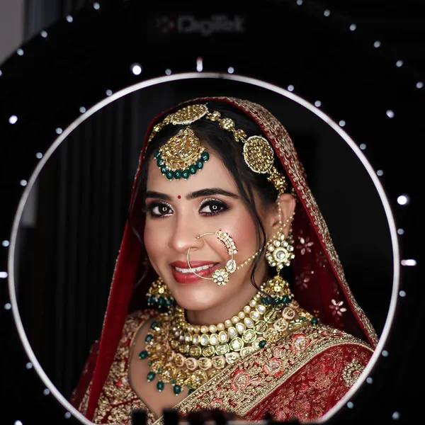 Bride in green and gold jewellery photographed under ring light