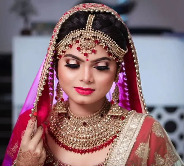 Bride in a magenta dupatta with gold bridal jewellery