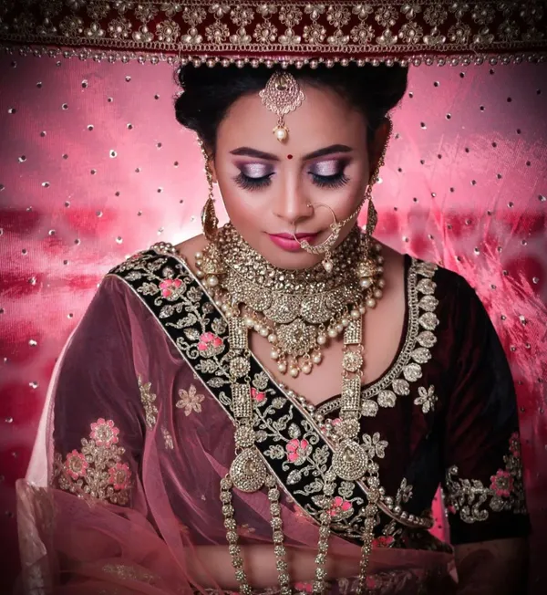 Bride in maroon with heavy traditional jewellery and a bold lip
