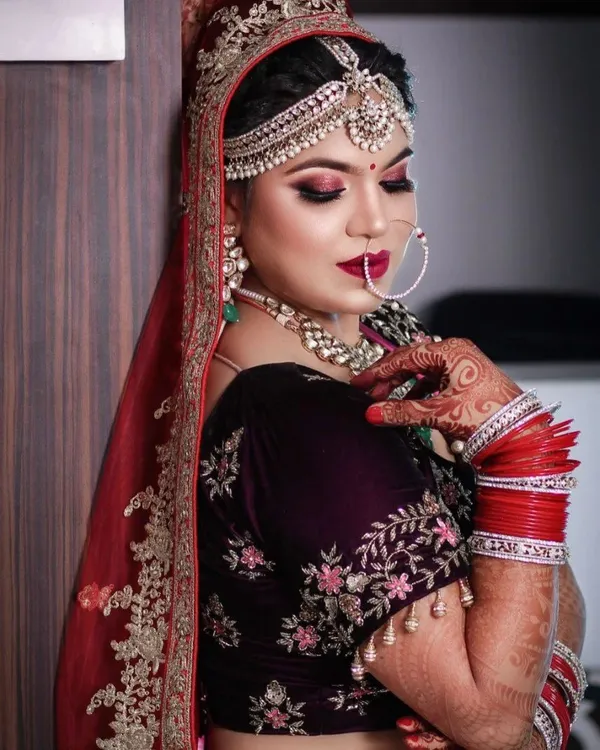 Bride in maroon with gold hoop earrings and a sleek finish
