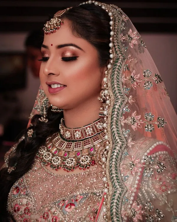 Side profile of a bride in a peach dupatta with gold jewellery
