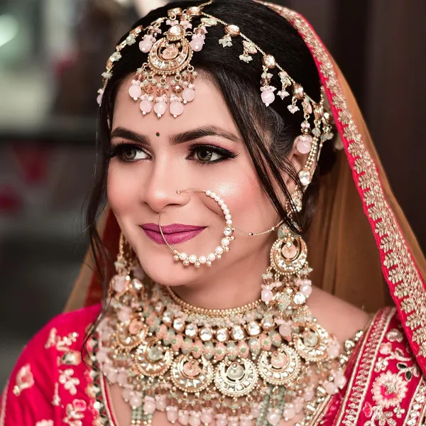 Bride in pink and gold wearing a traditional nath